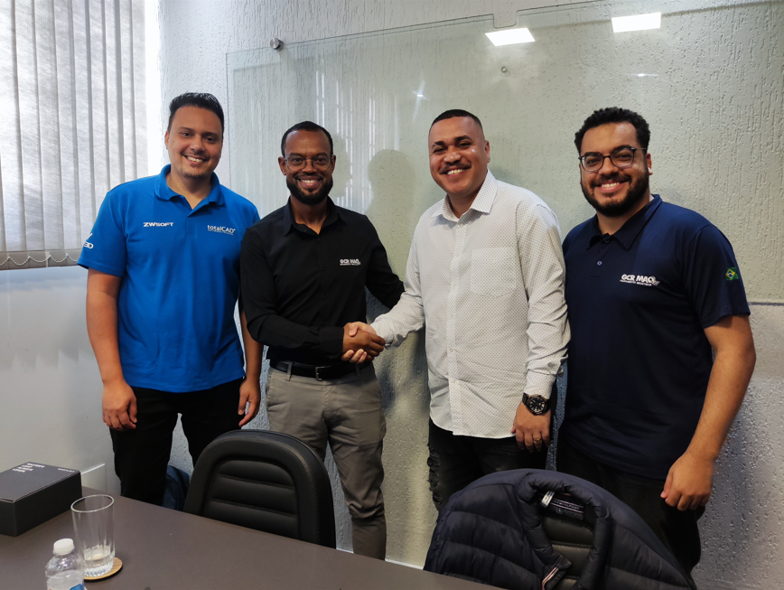 Membros da equipe da totalCAD e membros da equipe da GCR MAQ de mãos dadas firmando a parceria.