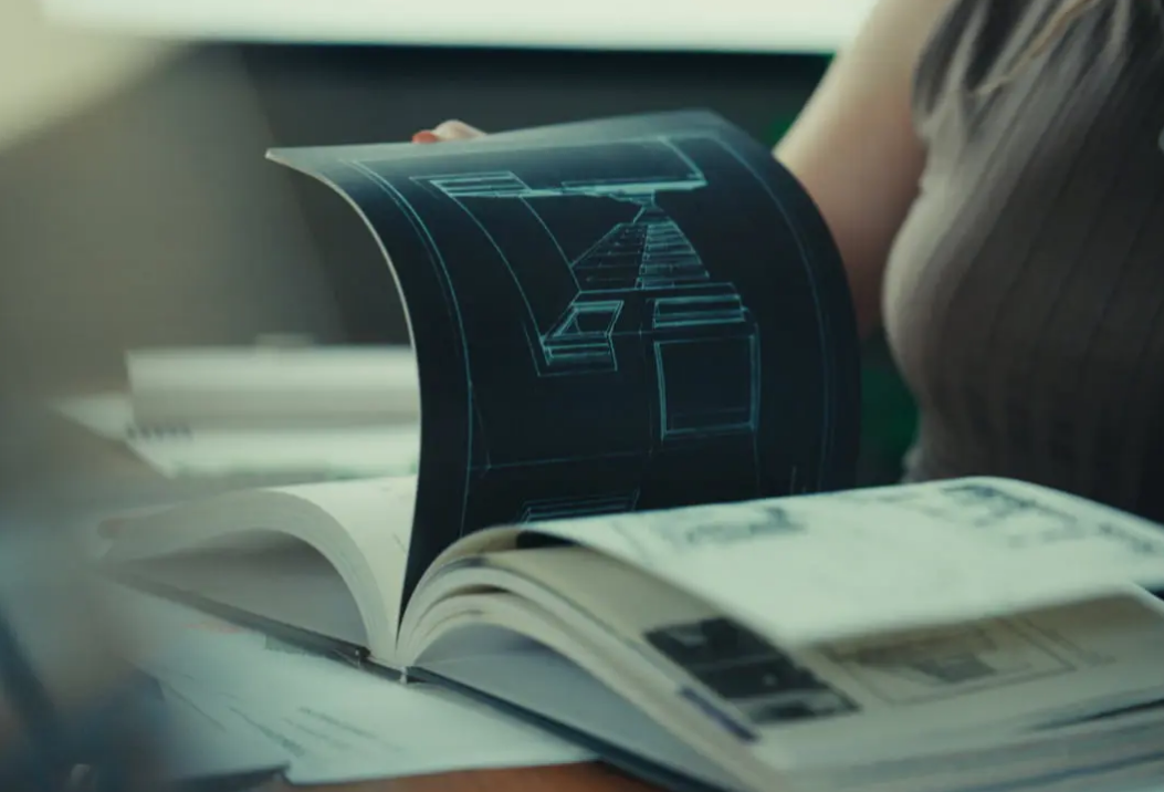 Kailey folheia um livro com imagens de maquetes de edifícios.